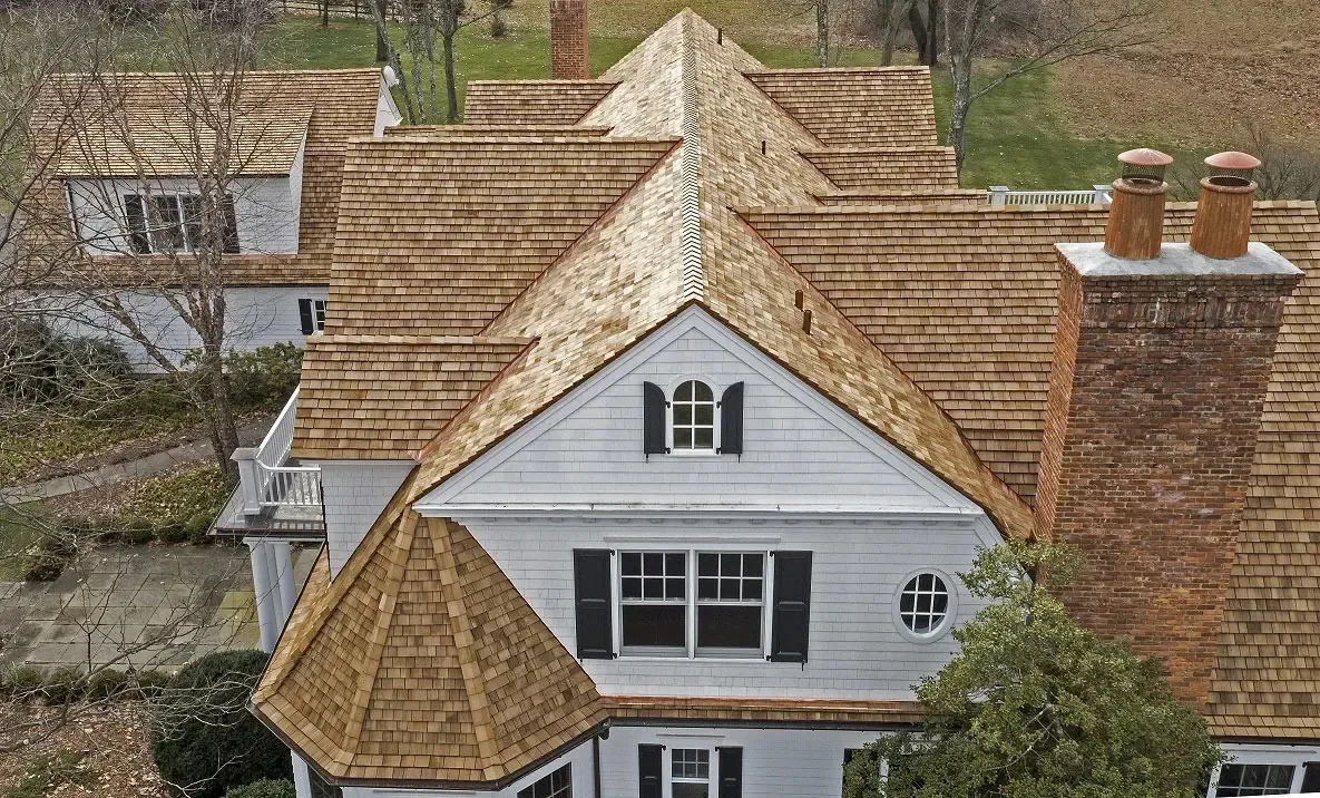 Natural wood roofing across intersecting rooflines on a white home